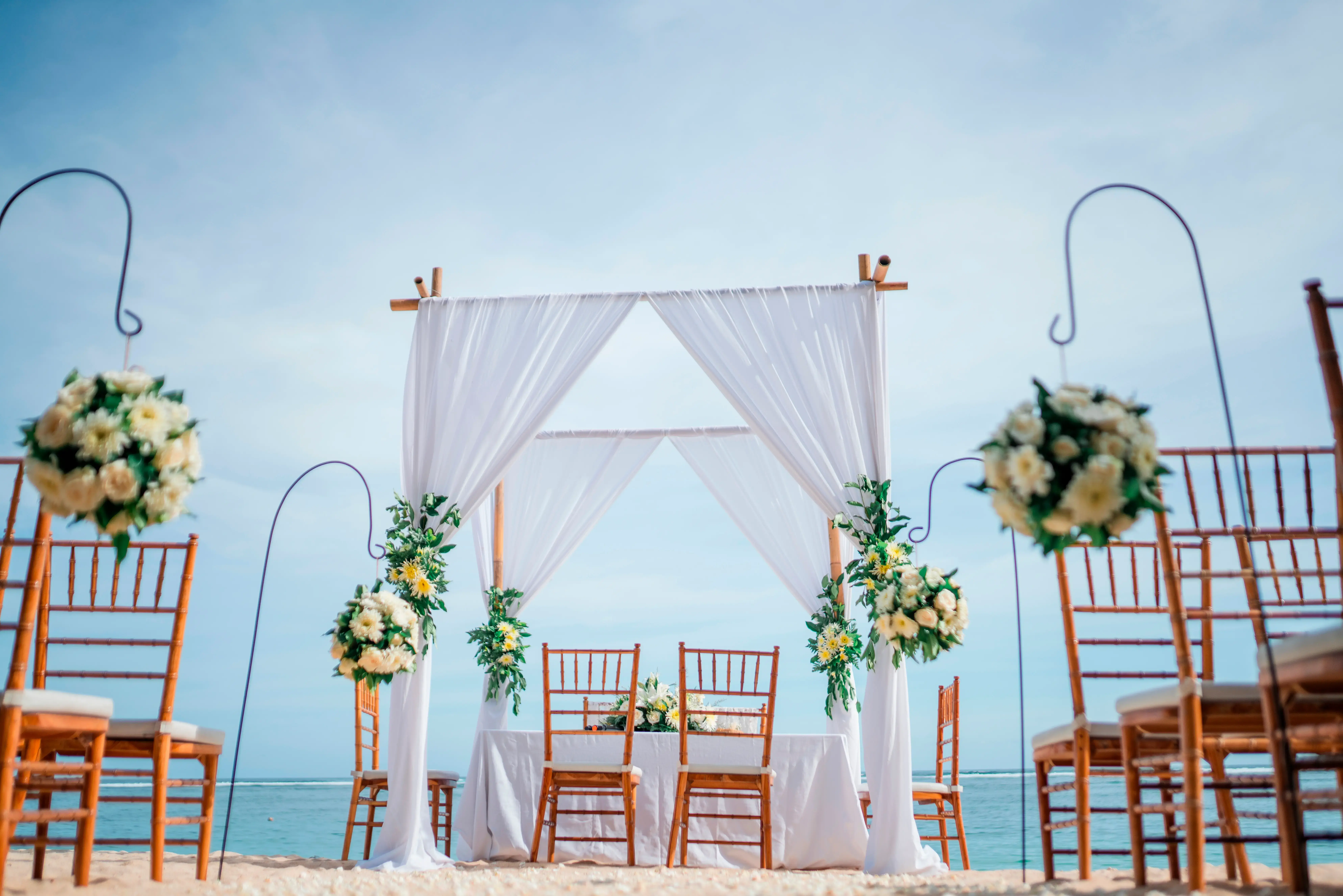 Ceremonia de boda en la playa con pérgola decorada con flores blancas frente al mar