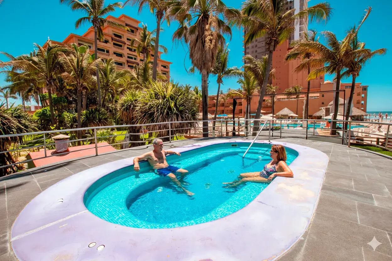 Huéspedes disfrutando de la piscina del resort con vista al mar y palmeras